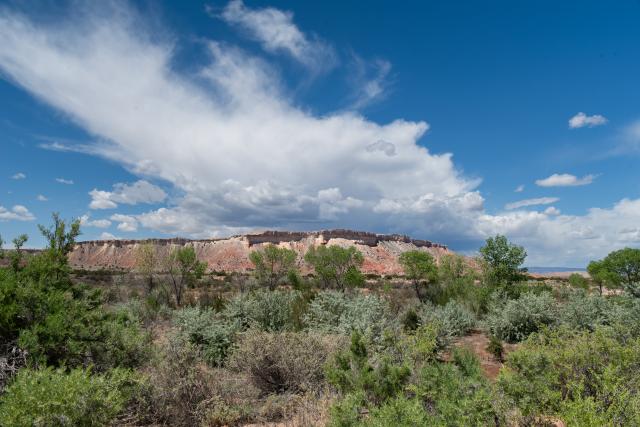 Clouds hovering over a butte in the distance. 