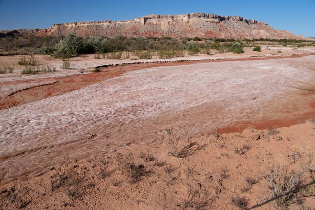 A dry riverbed with a butte in the distance. 