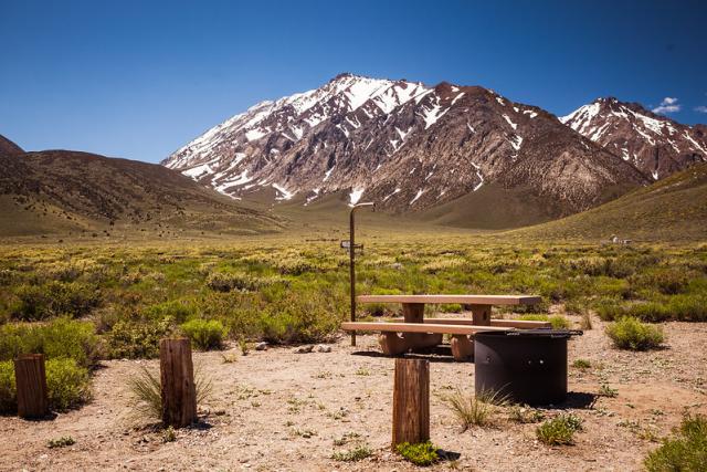 An empty campsite under a snow covered peak