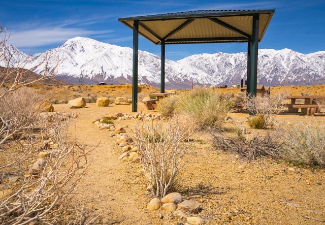 A sunshade in a campground with now covered mountains in the background