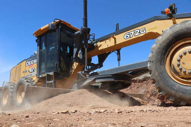 A road grader works on a gravel road.