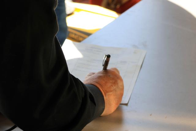 A hand holding a pen signing a piece of paper