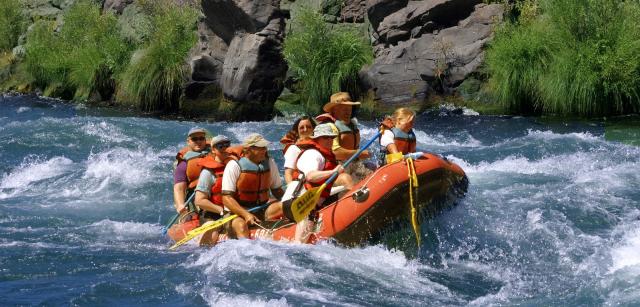 group of folks in personal flotation devices floating on the river in a boat