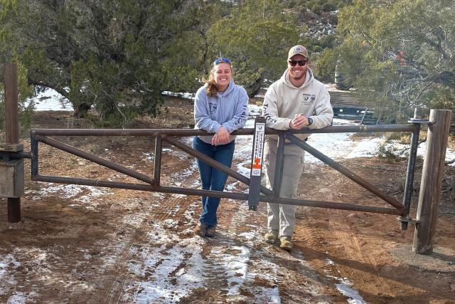 Two BLM employees stand behind a locked gate marking the seasonal closure at Electric Hills in the Uncompahgre Field Office.