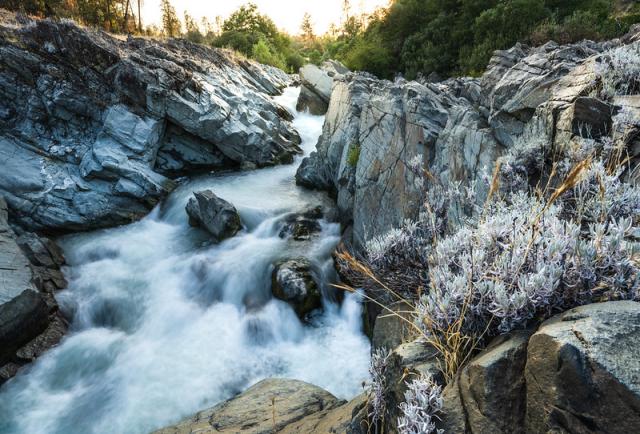 A creek rushes through a narrow gorge under a sunset.