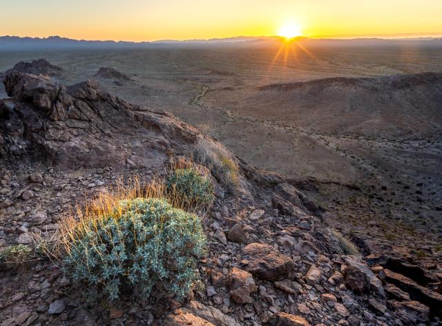 Sun sets over a massive alluvial fan in the desert