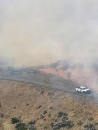 A truck on a dirt road on a steep slope with smoke