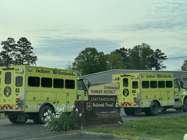 2 yellow firefighting vehicles are parked near the entrance sign for the Chattahoochee National Forest