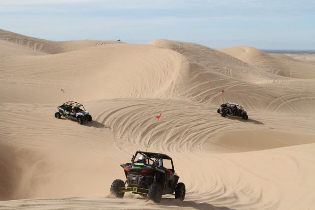 Three riders exploring a series of dunes