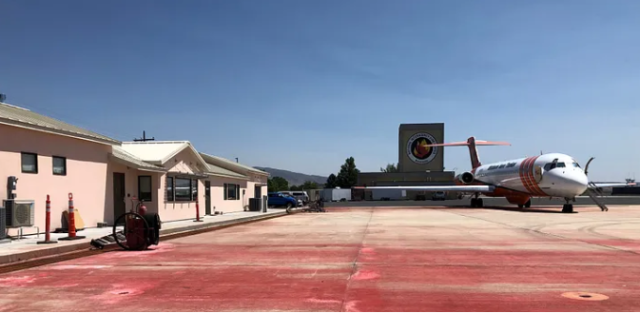 An airplane on tarmac outside a building