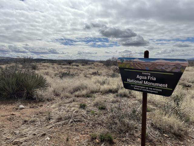 in a desert landscape, a trapezoid shaped sign says Agua Fria National Monument, US Department of the Interior, Bureau of Land Management