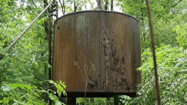 A hulking, rusted oil tank in overgrown forest in western Pennsylvania