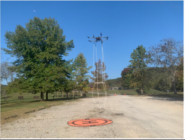 AQ drone takes off with what looks like a white wire net hanging underneath it. 