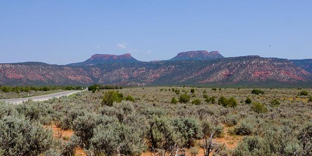 Two flat-topped features, or buttes, known as Bears Ears seen at a distance.