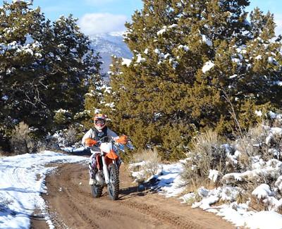 A dirt bike rider on a snowy path in the high desert