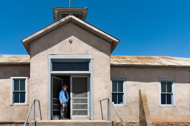 A man standing on the doorway of a restored schoolhouse.