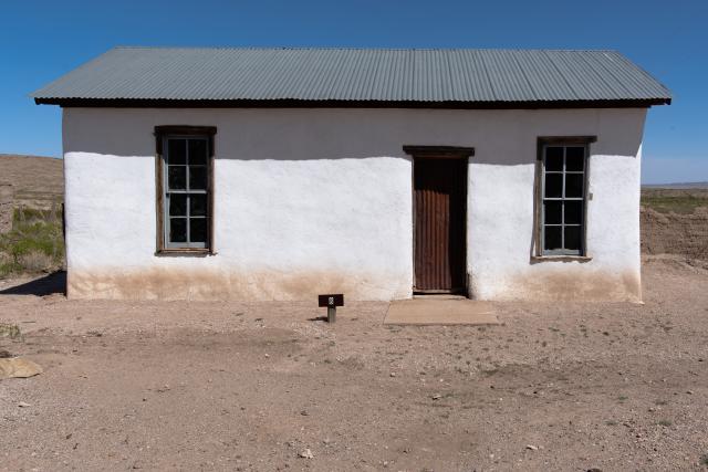 A house with two windows along a dirt road.