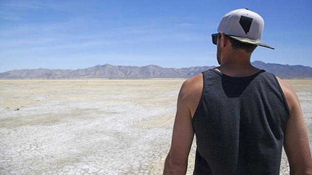 Person with a Nevada ball cap looking out over a desert playa