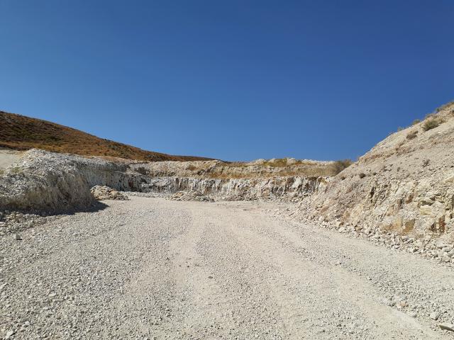 Zeolite mining area in Idaho. Gravel road with low zeolite walls and blue sky in background.
