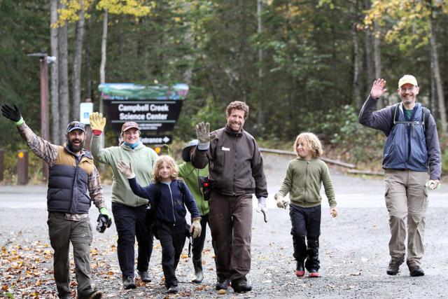 Volunteers wave as they walk down the road wearing work gloves.