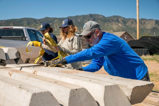 three adults work remove webbing from concreate parking markers