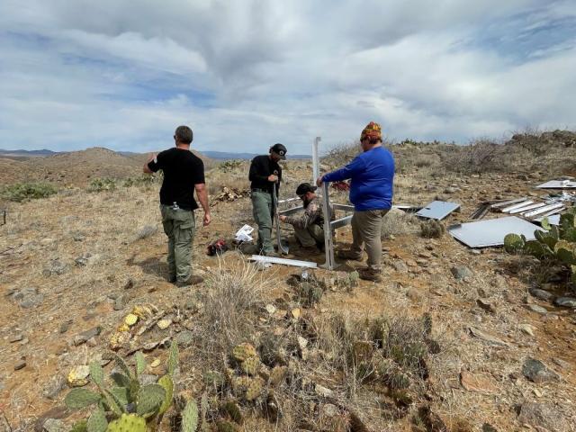 a group of people in a desert landscape construct a metal frame