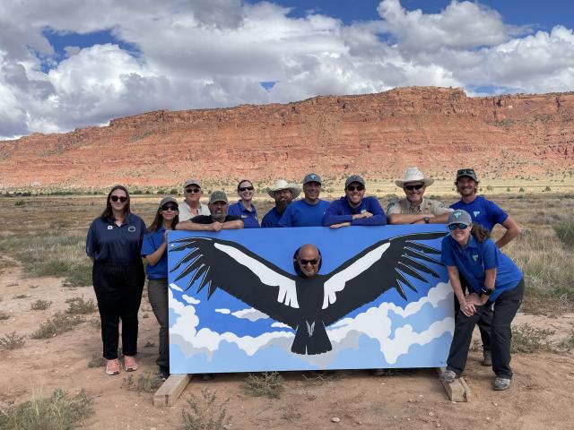 People pose with a mural of a California Condor 
