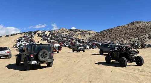 Off Road Vehicles line up around a sand and  rock mountain