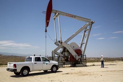 An inspector walks around a pump jack.
