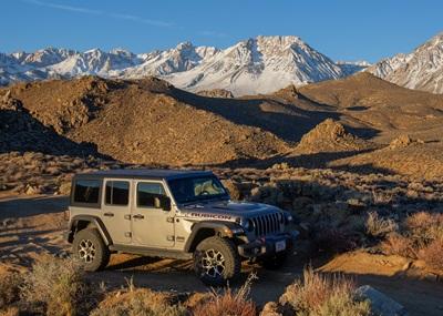 A grey Jeep with brown and snowy mountains in the background.