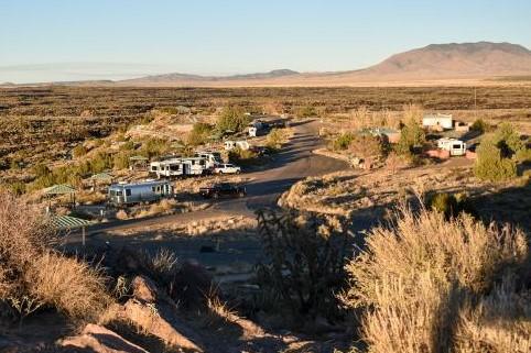 Vehicles in developed campground with pavilions in desert landscape