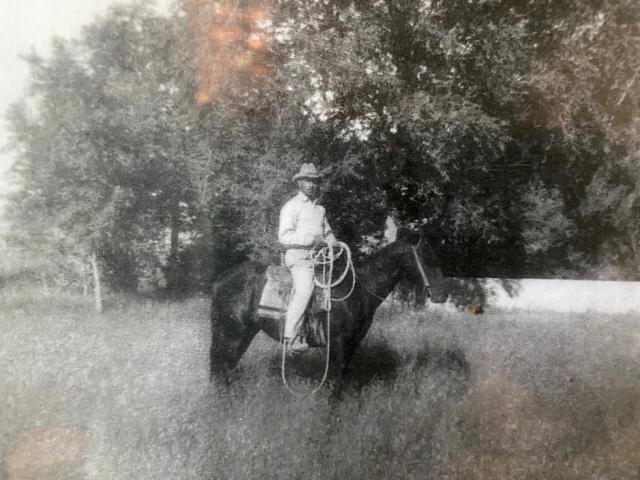 JT Bennett in a black-and-white photo on a horse in the field