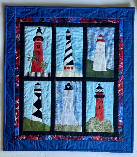 Quilt featuring six colorful lighthouse panels with names and dates, framed by blue and multicolored borders.