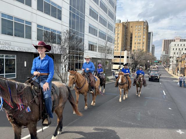 Group of people on horseback ride through an urban setting
