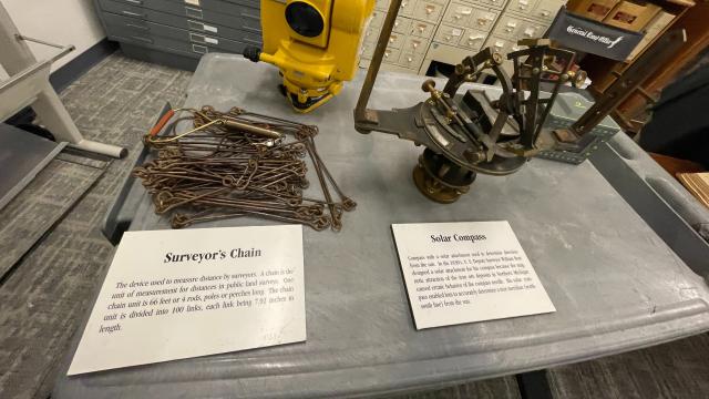 Surveyor’s Chain and Solar Compass displayed on a table, used for measuring distances and determining direction from the sun in land surveying.