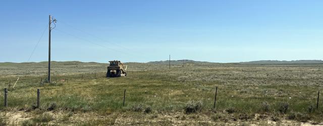 Overhead powerlines and poles extend across a prairie landscape.