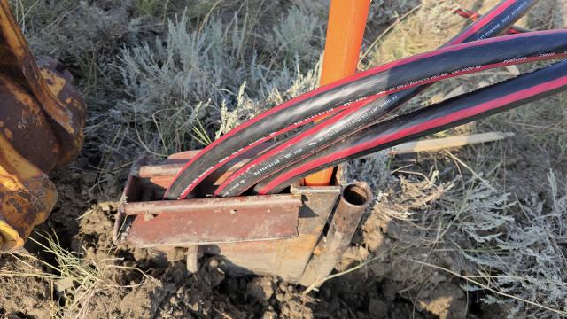 Power and cable lines are threaded through a specialty plow assembly for underground placement.