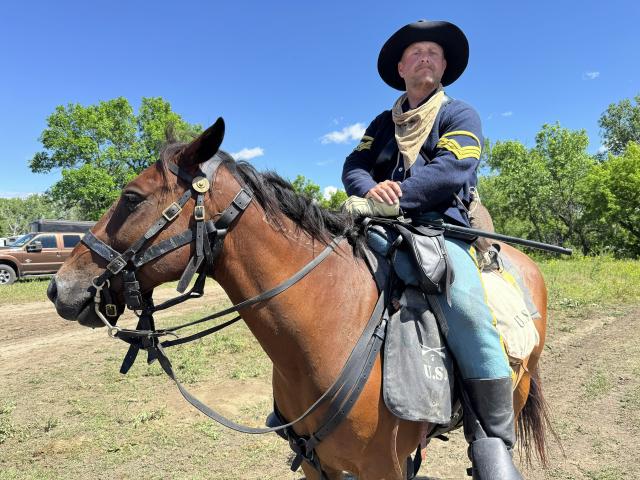 An individual posed on a horse wearing historical garb