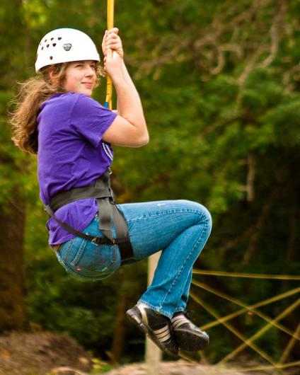 person in a helmet riding a zipline