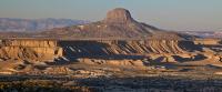 The volcanic plug of Cabezon Peak with long shadows on the cliffs in the foreground.