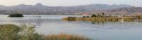 a lake with grassy islands and distant mountains