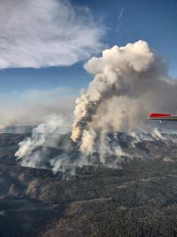 smoke from a wildfire billows up from a mountain