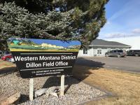 Dillon Field Office Sign. Large tree and office building in background.