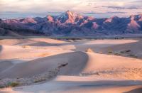 Sunset set turns the mountains and sand dunes shades of pink, orange, and purple at the Little Sahara Recreation Area. BLM photo by Bob Wick. 