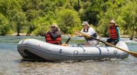 three people with life jackets in a white water raft.