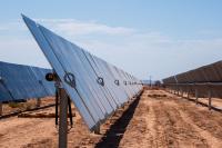 Rows of newly constructed solar panels in a dirt field.