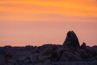 Large rocks under a orange sunset.