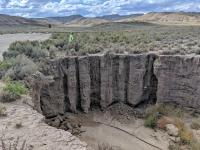 A man stands on a bank that has suffered from erosion.