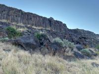 Black Cliffs Climbing Area, grass in foreground, rock face, and blue sky in background. 