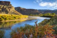 A river winds through a fall-colored landscape with rock formations rising in the background.